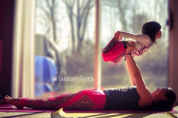 niña es sostenida por su madre mientras hace postura de yoga