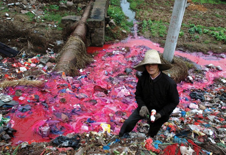 Mujer juntando botellas de plástico en un río contaminado de color rojo en china