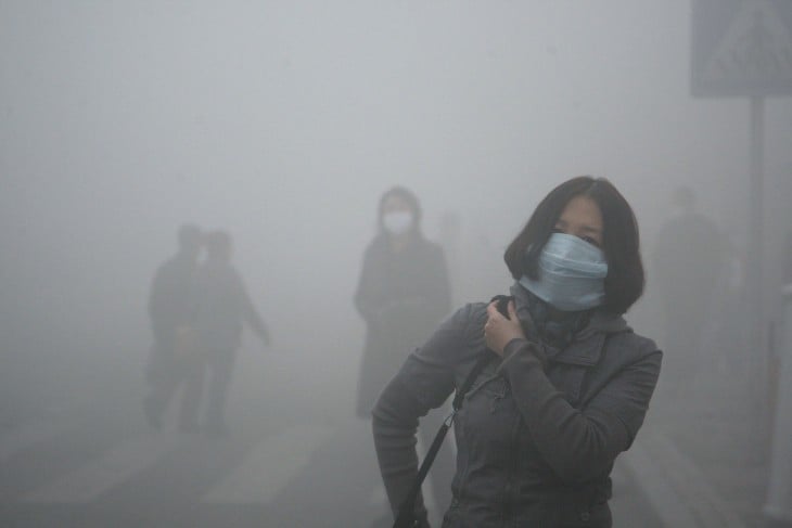 Chica camina con un barbijo por las calles de Beijin, donde la polución es 40 veces mayor a los estándares internacionales de seguridad