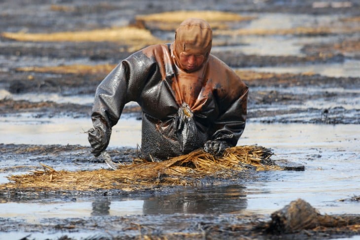 Trabajador intentando quitar el petroleo del agua, Dalian, Liaoning