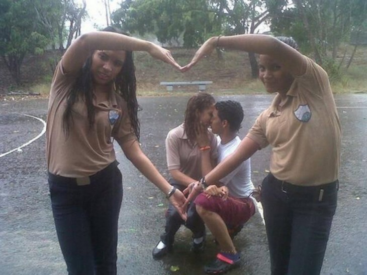 Amigas formando un corazón mientras una pareja se besa