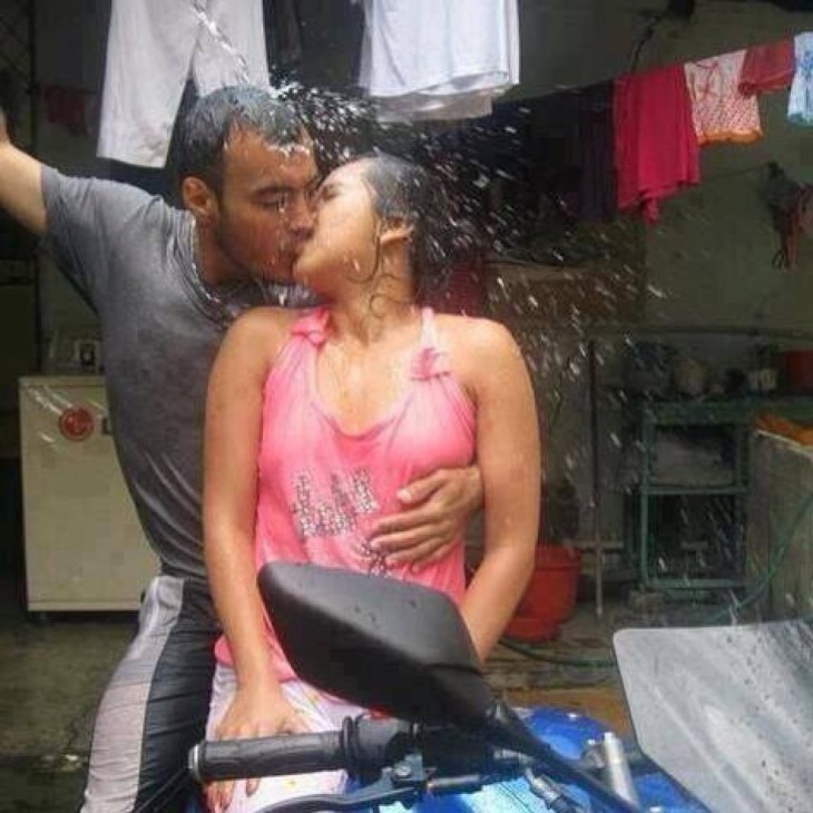 Dos enamorados en una moto bajo el chorro de agua