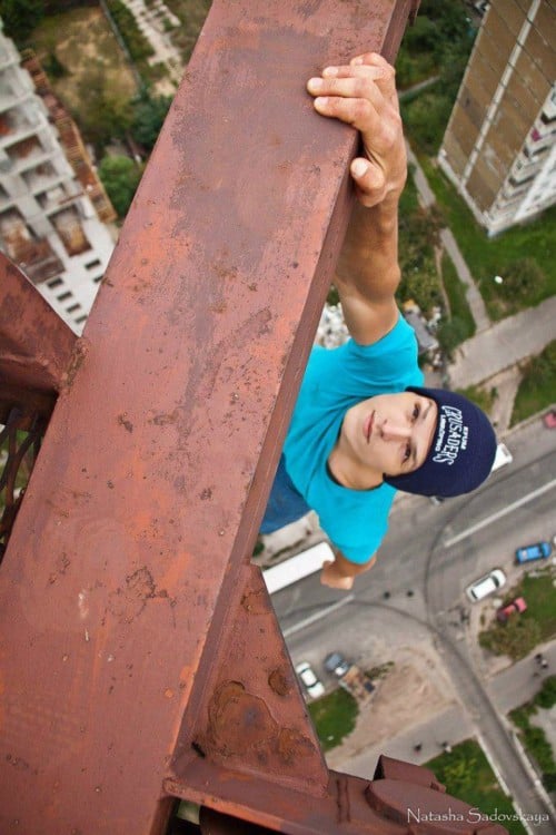 hombre agarrado de una viga en la altura