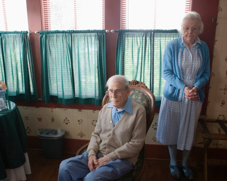 pareja de abuelos en el living y un hombre aspirando