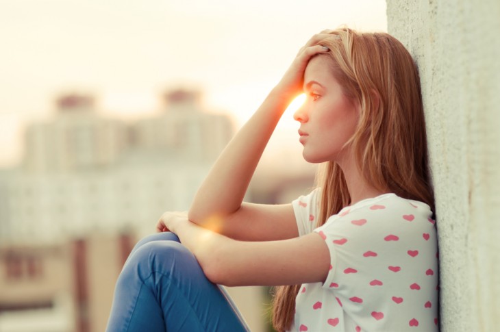 mujer tocandose la cabeza porque pensando durante el atardecer