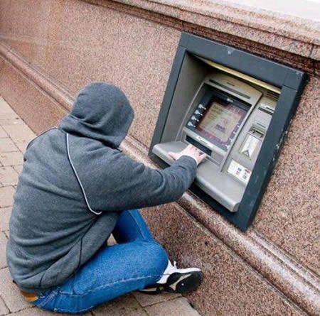 hombre sacando dinero de un cajero automático sentado en el suelo 