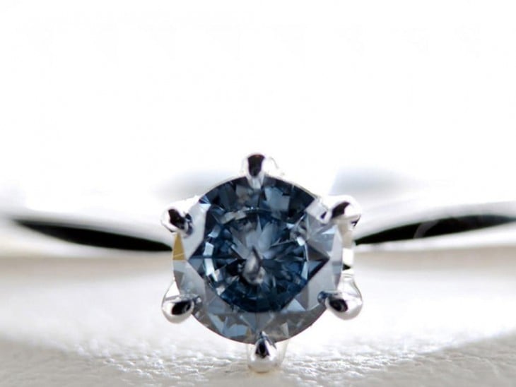 Diamante en color azul subido sobre una superficie blanca 