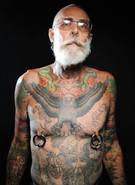 hombre de edad avanzada con tatuajes en todo el cuerpo y perforación en los pezones 