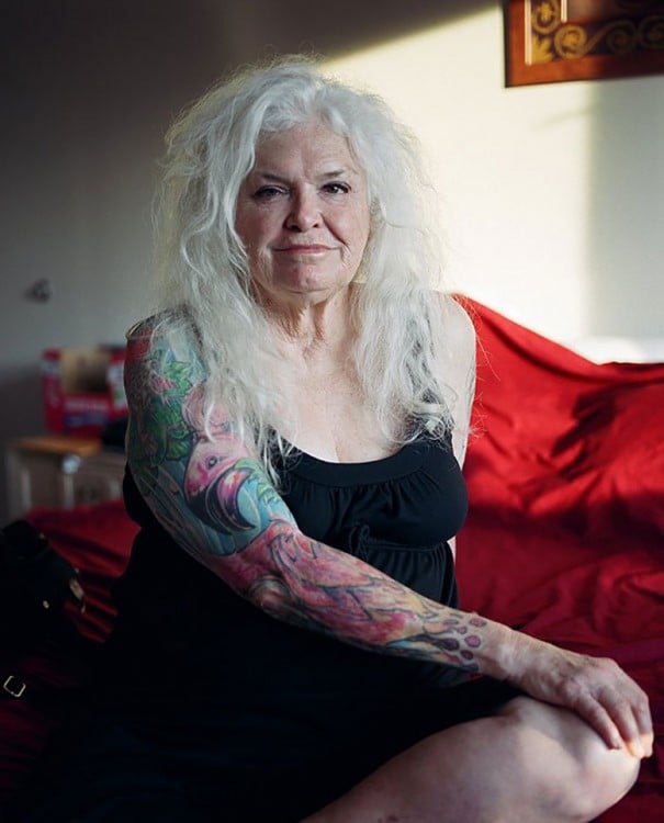 Mujer adulta de cabello blanco con tatuajes en los brazos 