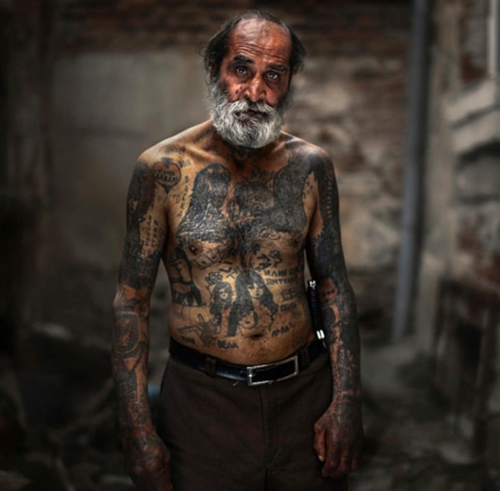 Hombre mayor sin camisa luciendo sus tatuajes del cuerpo 
