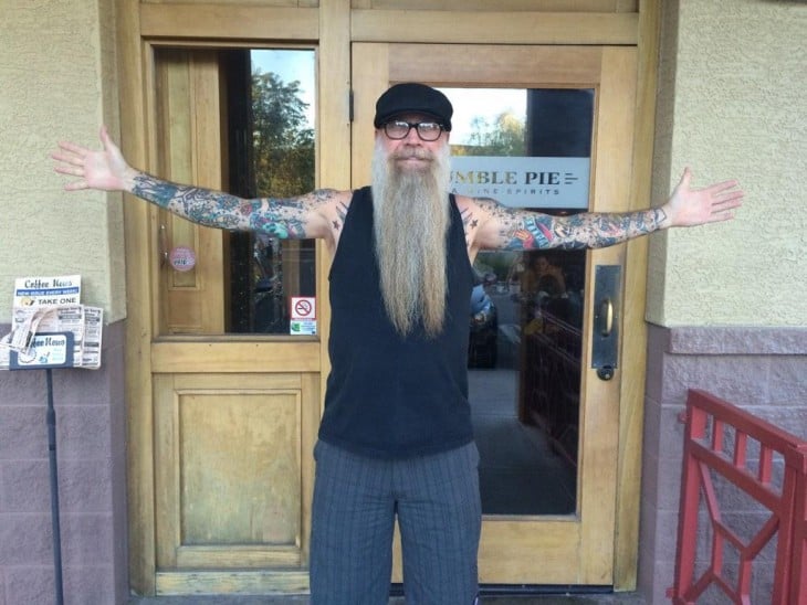 hombre mayor con barba larga y brazos tatuados 