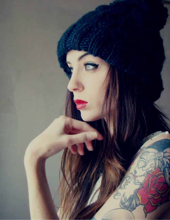 Chica con gorro negro y tatuajes en un brazo