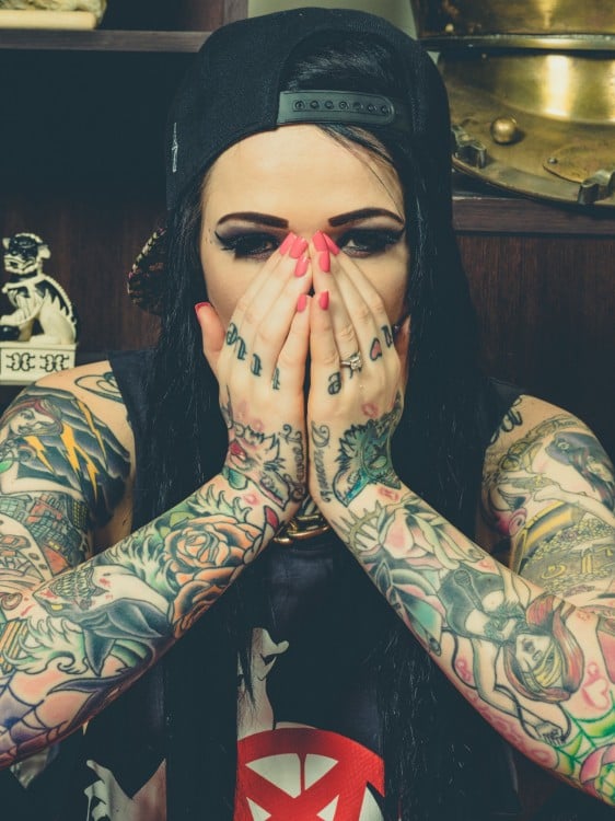 mujer con gorra negra y todos los brazos tatuados