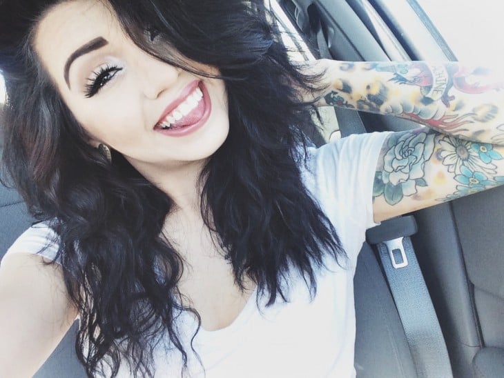 Chica sonriendo con un brazo tatuado