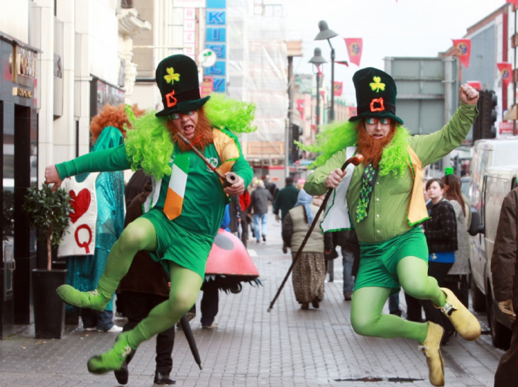 personas vestidas de duendes bailando y desfilando por la calle 