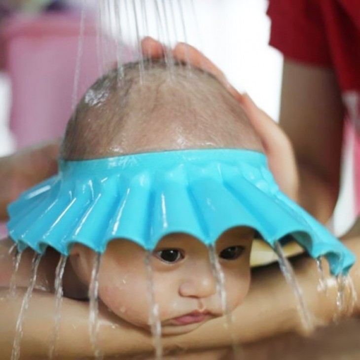 Bebé con gorra de baño especial para que no le caiga agua en la cara 