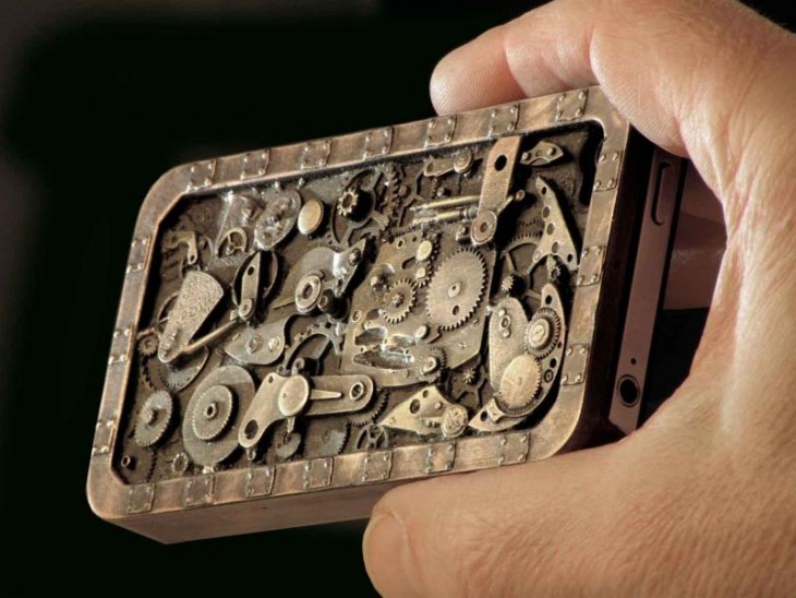 Mano de un hombre sosteniendo un Iphone con una funda de diseño de un mecanismo steampunk 