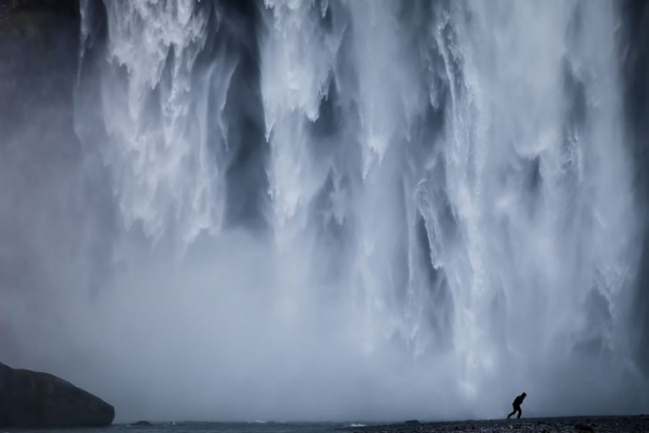 Persona corriendo debajo de unas enormes cascadas ubicadas en Islandia 