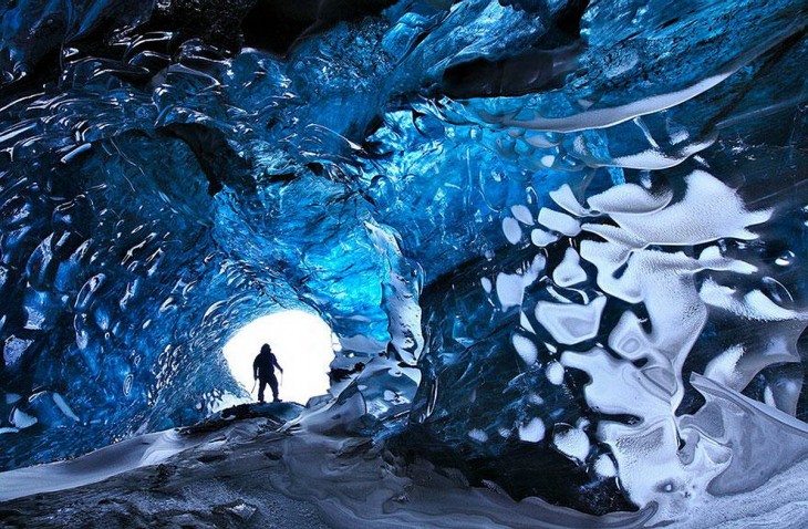 Un hombre parado en la entrada de un túnel denominado la cueva de cristal en Islandia 