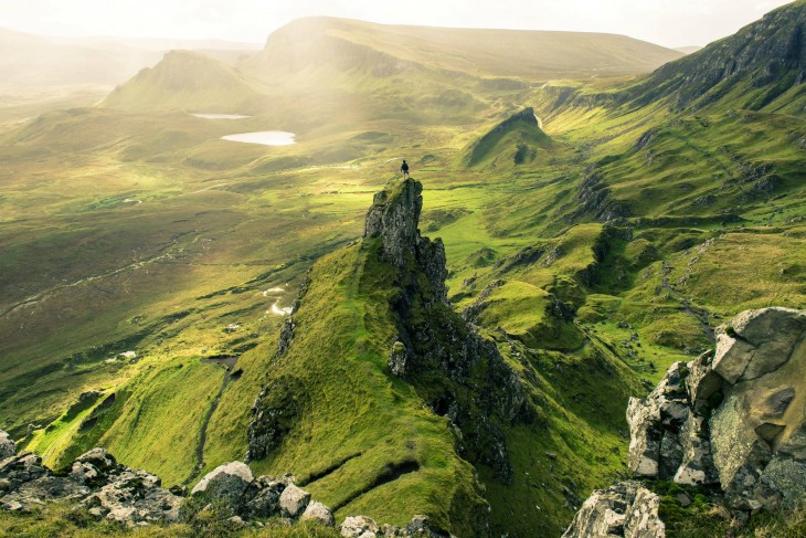 Hombre en la cumbre de una montaña con pastizales verdes en un ambiente cerca de Escocia 