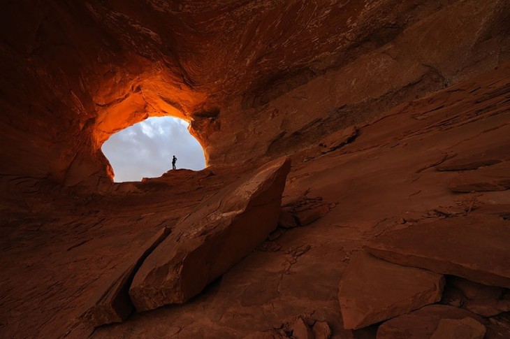 Lugar lleno de rocas como una montaña y una persona la final parada sobre la entrada a este lugar 