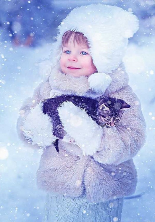 Niña en la nieve con un gato en sus brazos 
