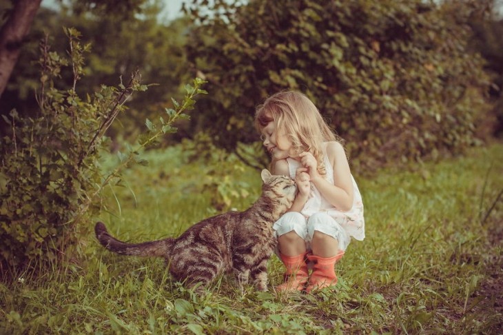 Una niña y su gato en un jardín 