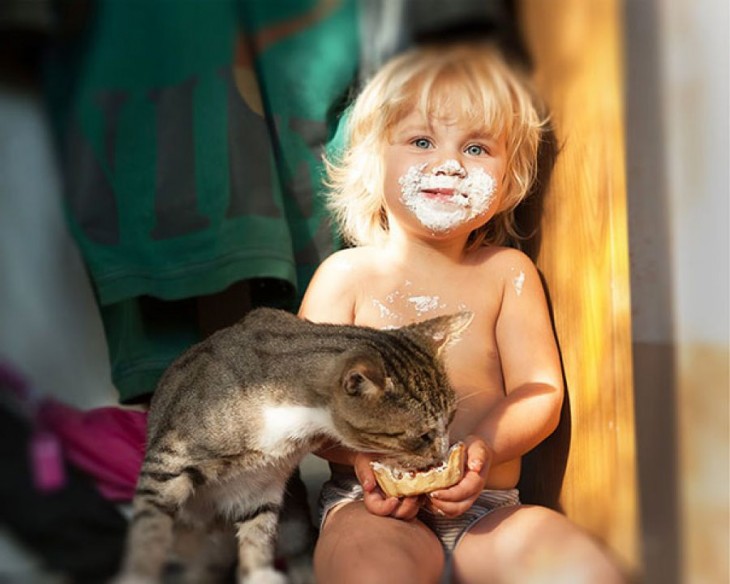 Niño sentado dando de comer a su gato 