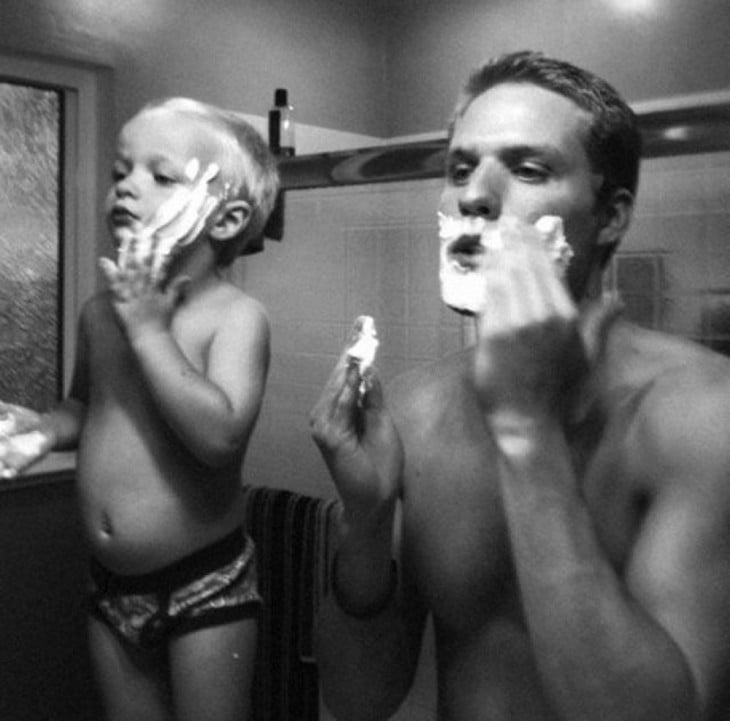 Padre e hijo rasurándose frente a un espejo 