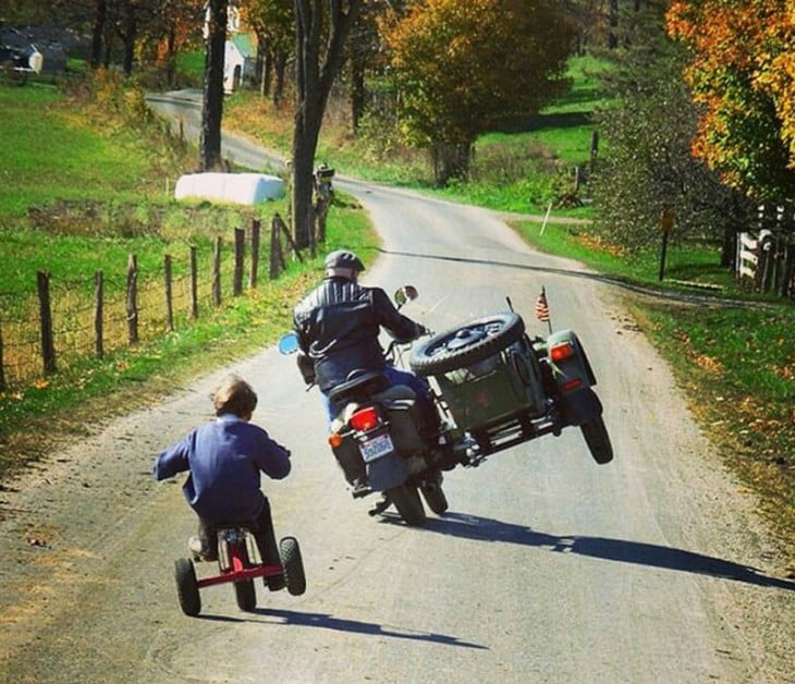 Padre e hijo haciendo la misma pose con su triciclo y motocicleta 