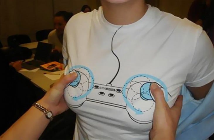 Playera con un control de videojuego y unas manos sobre el mismo 