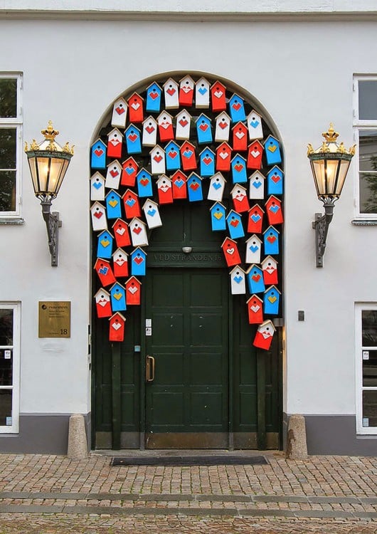 Puerta en Dinamarca con algunas pequeñas casitas de madera en diferentes colores en la parte superior 