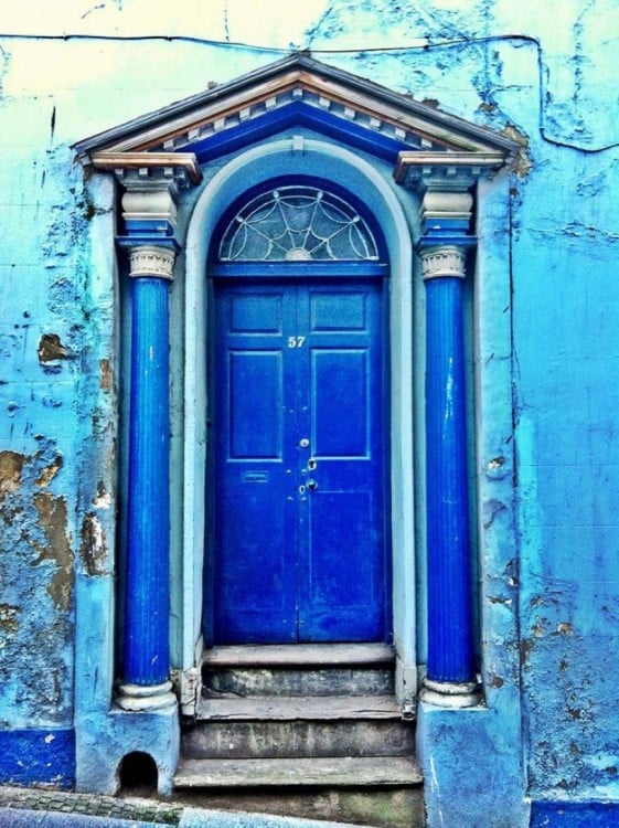 Puerta azul con barrotes en color azul con algunos escalones 