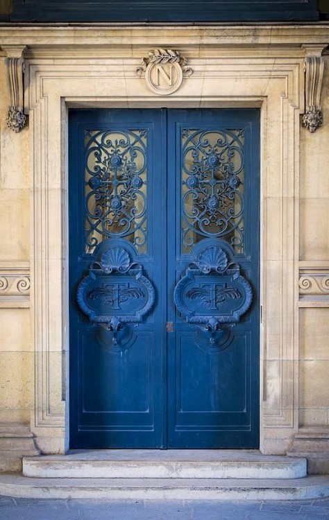 Puerta en color azul con barrotes y herrería con formas de flores 