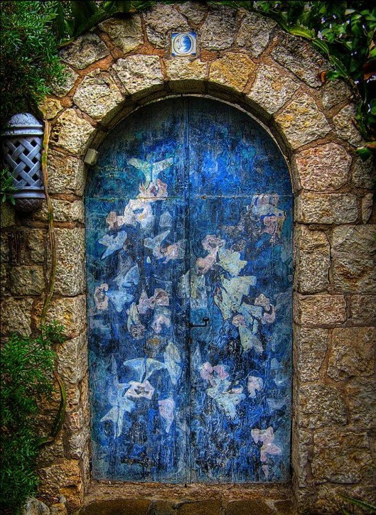 Puerta que esta decorada en color azul y en su marco tiene contorneado por piedras 