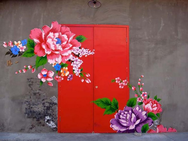 Puerta en color rojo con diseños de flores que van desde sus paredes en diferentes colores 