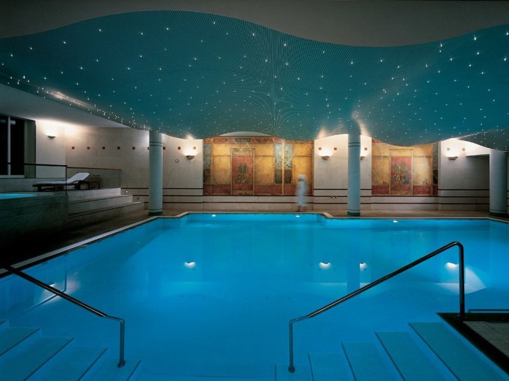 Piscina de un spa con un techo en color verde azulado con pequeños puntos que simulan ser estrellas y son unas pequeñas luces 