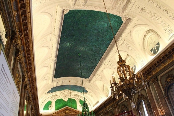 Salón de los espejos en Bélgica con un techo con estilo de iglesia y espacios en un color verde obscuro muy elegante 