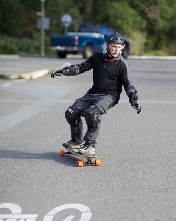 Hombre de la tercera edad en patineta por la calle 