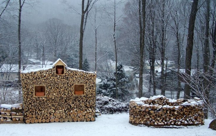 Troncos de madera juntos formando una pequeña casita con tres ventanas y un medio círculo en un cosatado 