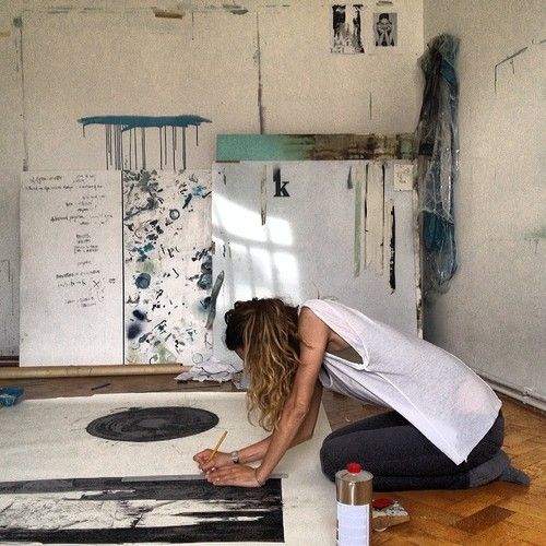 mujer hincada pintando un cuadro en el suelo 