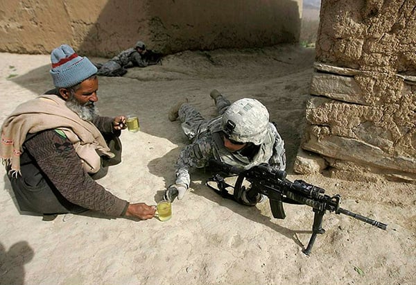 hombre dándole una taza de té a un soldado en la guerra 