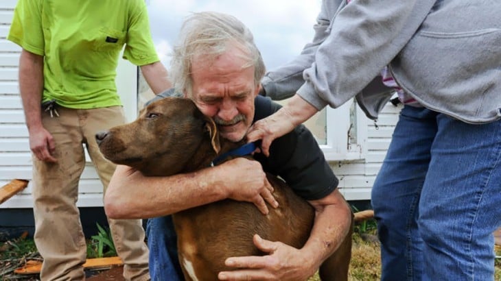 hombre abrazando a sus perro luego de encontrarlo en los escombros de una casa en ruinas 