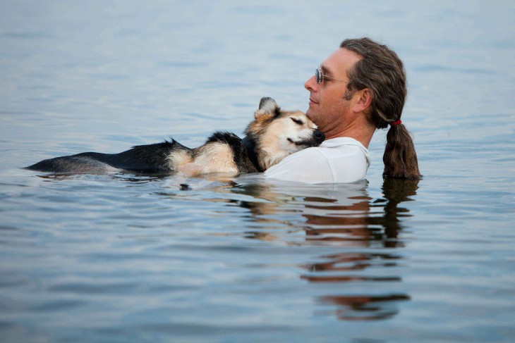 hombre sosteniendo a un perro dentro de un lago 