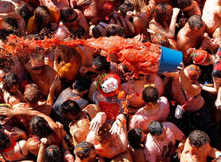 personas en una calle lanzándose tomates