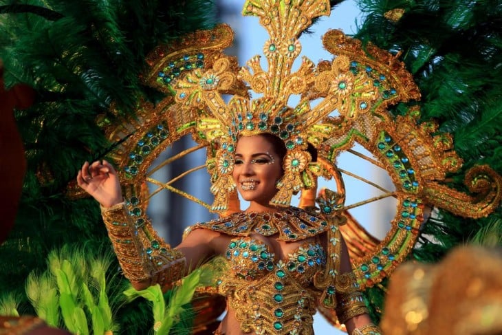 mujer usando un traje de piedras amarillas y azules con plumas 