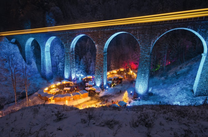 tiendas de un mercado bajo el puente iluminado con luces de navidad en Alemania 