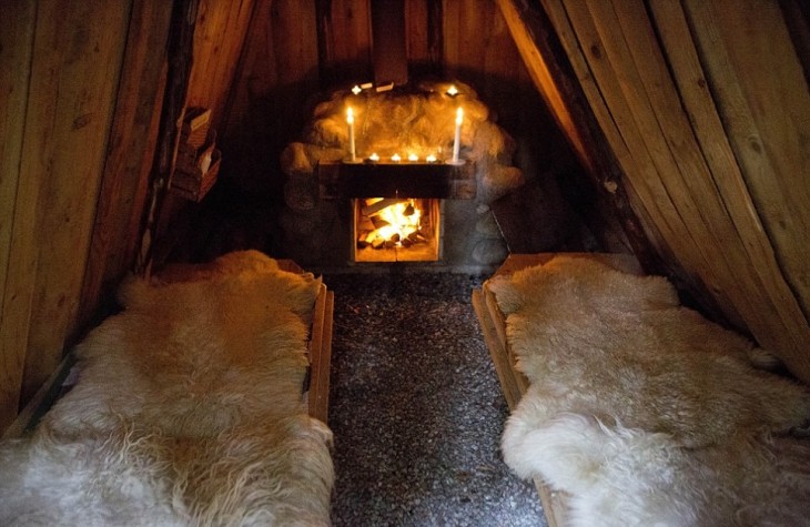 cabaña que cuenta con una chimenea y camas hechas con piel de animales 