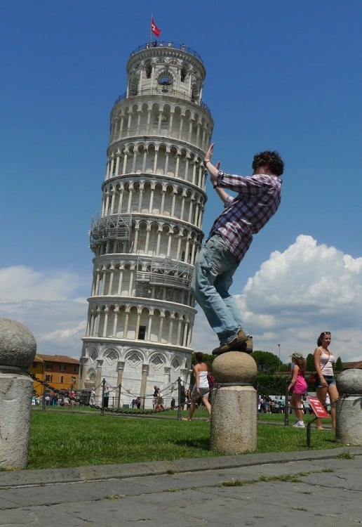 chico con camisa escocesa sostiene la torre de Pisa