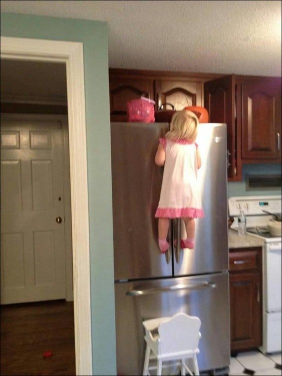 niña sobre una silla colgando de un refrigerador 